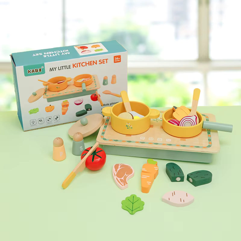 Children's toy kitchen set with wooden pots, pans, and food items on a light green surface.