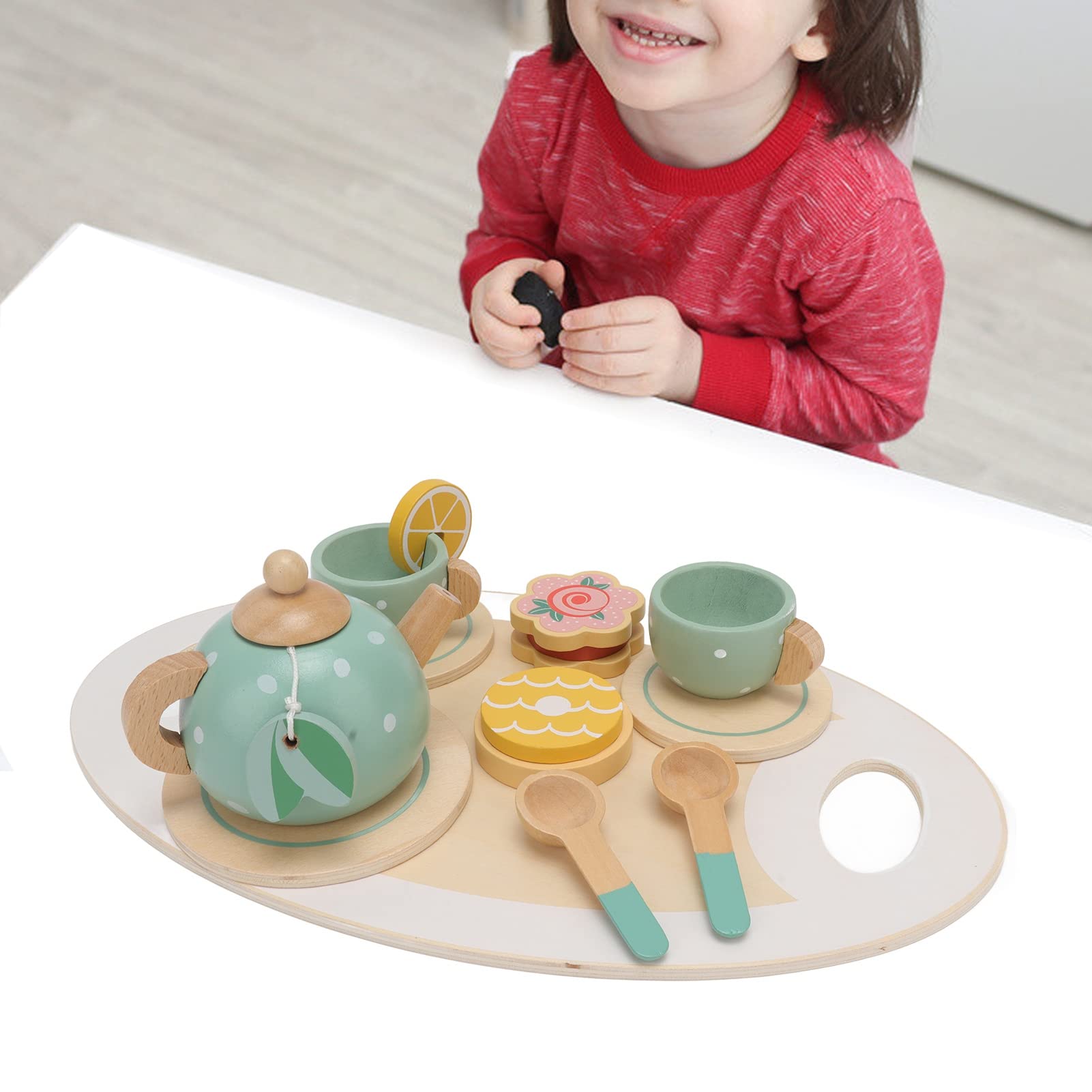 Child playing with a toy tea set on a table