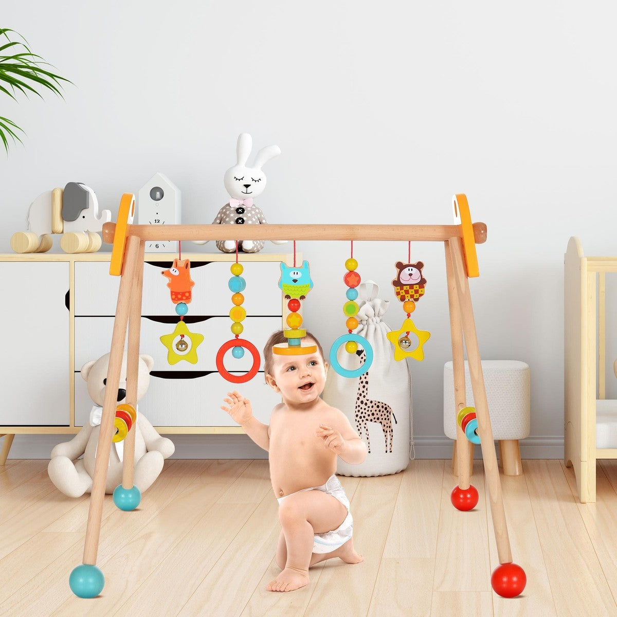 Baby playing with a colorful wooden baby gym in a room with toys and furniture.
